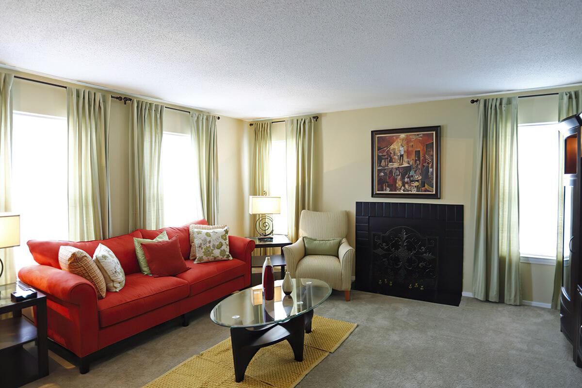 Living room with red sofa, coffee table, and bright curtains.